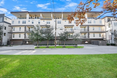 Modern building with a clean, white façade and several balconies. The property is surrounded by well-maintained greenery and trees, providing a pleasant curb appeal.