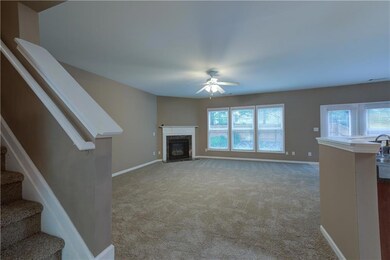 Unfurnished living room with ceiling fan, stairs, carpet flooring, and baseboards