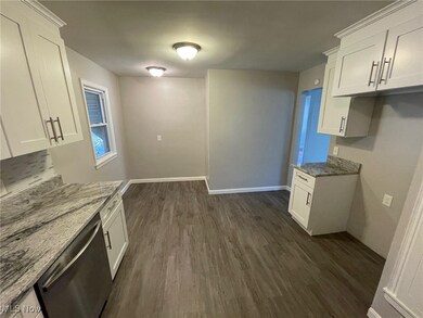 Kitchen featuring dishwasher, white cabinetry, and stone countertops