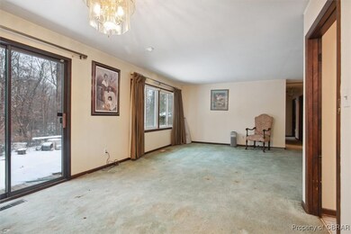 Carpeted empty room featuring an inviting chandeli