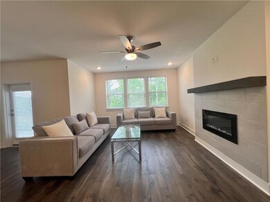 Living room with dark wood-style floors, ceiling fan, a fireplace, and recessed lighting