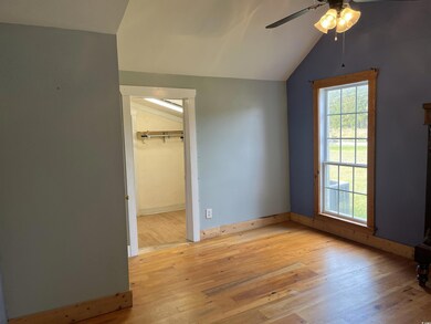 Unfurnished bedroom featuring lofted ceiling, light wood-style floors, a walk in closet, and ceiling fan