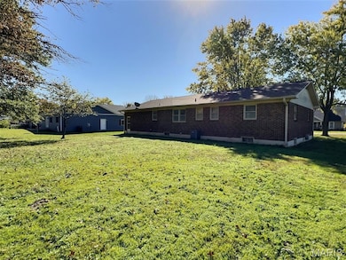 Rear view of house featuring brick siding and a lawn