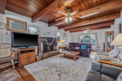 Living area featuring beamed ceiling, a baseboard 