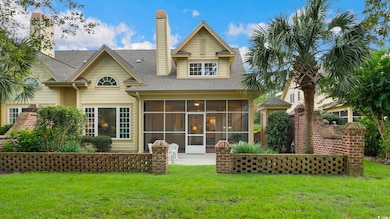 Rear view of property with a sunroom, a lawn, and a shingled roof