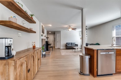 Kitchen with open floor plan, dishwasher, open shelves, a ceiling fan, and light wood-style floors