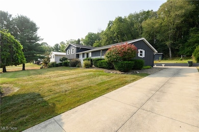 Split level home featuring board and batten siding, a front lawn, and view of wooded area