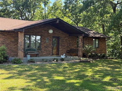 View of front of house with brick siding, a front lawn, and a shingled roof