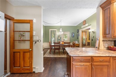 Kitchen with light stone counters, a textured ceiling, crown molding, and dark hardwood / wood-style flooring