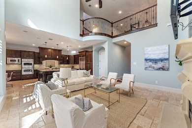 The family room features stone floors, high ceilings, and a fireplace. Its seamless connection to the island kitchen highlights its role as the heart of the home.
