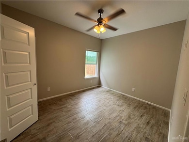 Unfurnished room featuring ceiling fan, dark wood finished floors, and baseboards