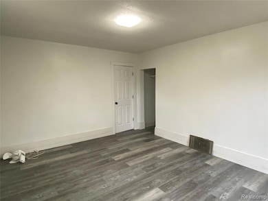 Empty room with baseboards and dark wood-style flooring