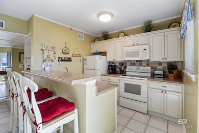 Kitchen featuring white appliances, ornamental molding, decorative backsplash, light tile patterned floors, and a peninsula
