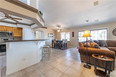 Living area with ceiling fan, visible vents, and l