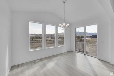 Unfurnished dining area featuring a mountain view, a chandelier, lofted ceiling, and light wood-type flooring