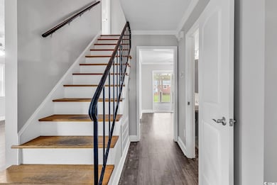 Staircase featuring ornamental molding and wood finished floors