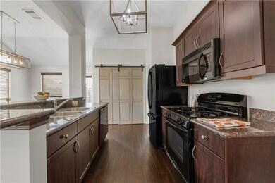 Kitchen with black appliances, a sink, dark wood-s