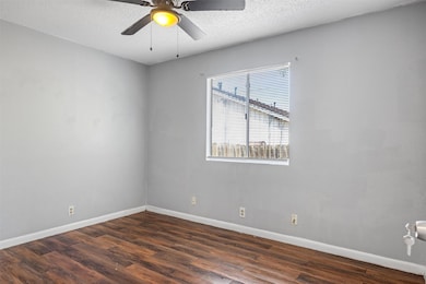 Unfurnished room featuring a textured ceiling, dark wood-style floors, and ceiling fan