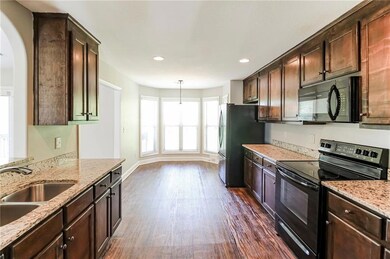 Kitchen featuring black appliances, dark wood-style flooring, dark brown cabinets, and recessed lighting