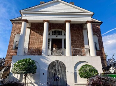 View of front of property featuring brick siding, a balcony, and a chimney