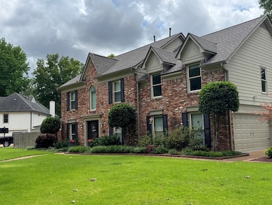 View of front of house with brick siding, a shingled roof, a front lawn, and an attached garage
