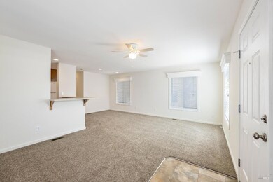 View of living and dining room from the front door, along with kitchen bar area.