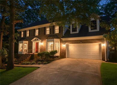 Colonial-style house featuring concrete driveway, brick siding, and a garage