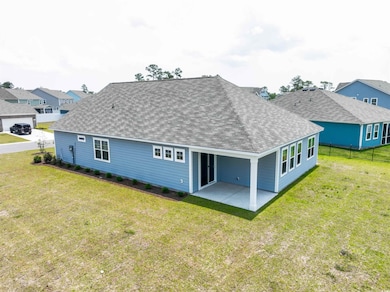 Rear view of property featuring a shingled roof, a patio, and a residential view