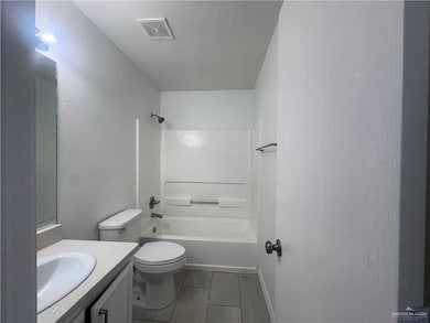 Full bathroom featuring vanity, washtub / shower combination, tile patterned floors, and a textured wall