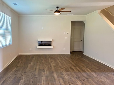 Unfurnished living room featuring ceiling fan, dark wood-style floors, and crown molding