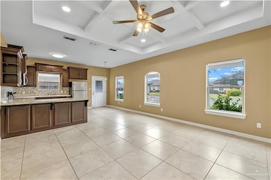 Kitchen with coffered ceiling, open shelves, backsplash, plenty of natural light, and freestanding refrigerator