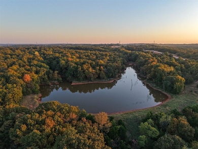 Aerial view of property and surrounding area featuring a heavily wooded area and a nearby body of water