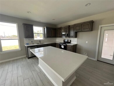 Kitchen with appliances with stainless steel finishes, a kitchen island, dark brown cabinets, light wood finished floors, and recessed lighting