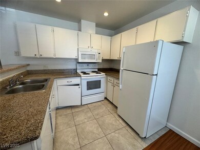 Kitchen featuring white appliances, a sink, dark c
