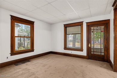 Unfurnished room featuring carpet flooring and a drop ceiling