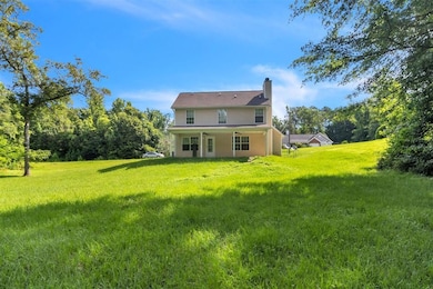Back of house featuring a chimney and a yard
