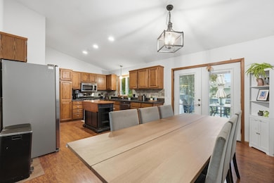 Bright kitchen and dining area with vaulted ceilings, Oak wood cabinetry, center island, and stainless appliances. Door leads to the backyard deck, perfect for entertaining and fun.