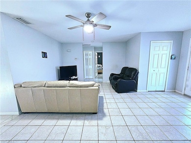 Living area with ceiling fan, baseboards, and light tile patterned floors