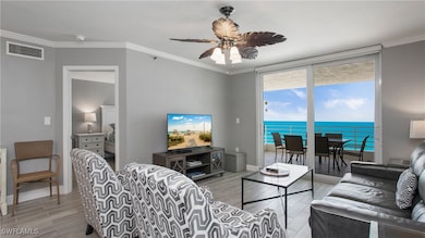 Living room featuring ornamental molding, wood finish floors, a ceiling fan, and floor to ceiling windows