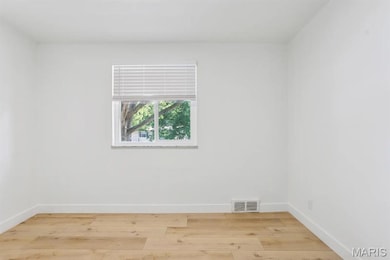 Spare room featuring baseboards and light wood-style floors