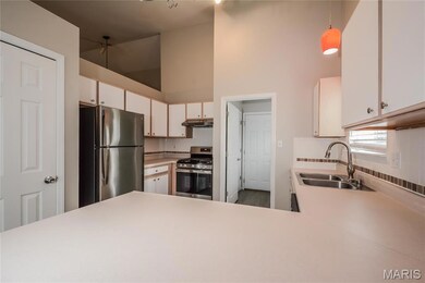 Kitchen featuring light countertops, stainless steel appliances, white cabinets, pendant lighting, and under cabinet range hood