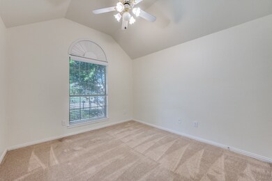 Empty room with vaulted ceiling, carpet flooring, and ceiling fan