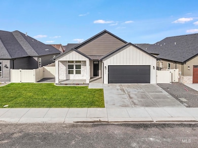Modern farmhouse style home featuring board and batten siding, a gate, a garage, and driveway