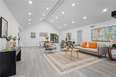 Living room featuring beam ceiling, light wood finished floors, high vaulted ceiling, and recessed lighting