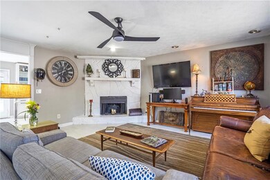 Living area featuring ceiling fan and a stone fireplace