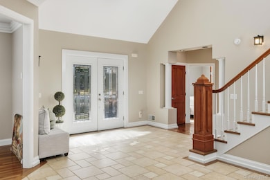 Entryway with french doors, high vaulted ceiling, and stairs