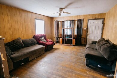 Living room featuring wood-type flooring, wood walls, and ceiling fan
