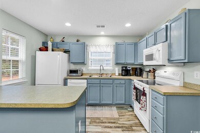Kitchen featuring white appliances, sink, light ha