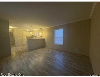 Unfurnished living room featuring crown molding and dark wood-style flooring