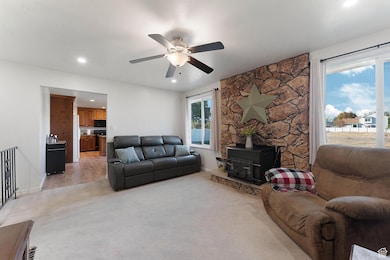 Living area featuring a wood stove, light colored carpet, recessed lighting, and ceiling fan